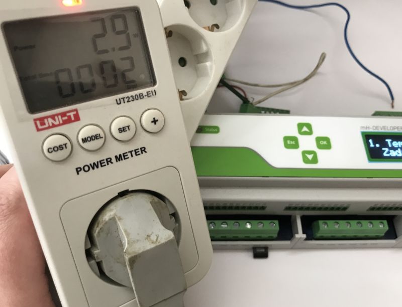 UNI-T electric power meter displaying energy consumption next to a control panel with an LCD display.