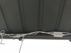 Białe przewody elektryczne przymocowane do metalowego zadaszenia.