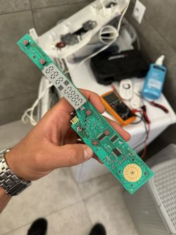 Osoba trzymająca płytkę elektroniczną z wyświetlaczem i przyciskami.