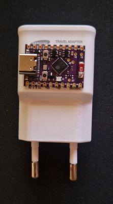 Photo of an ESP32 on a black breadboard with USB cables, placed on a desk in front of a monitor.