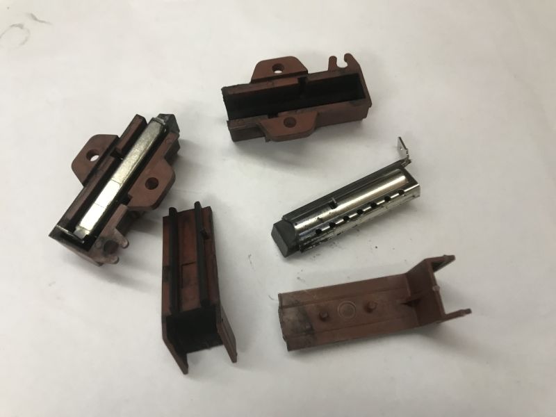 Worn-out washing machine motor brushes and enclosures on white background