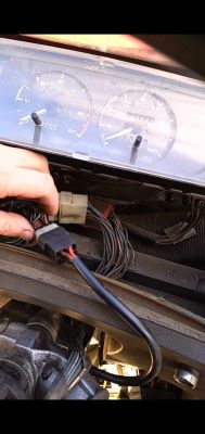 Deska rozdzielcza samochodu z widocznymi przewodami i dłonią odłączającą immobilizer.