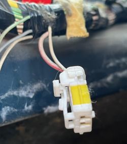 Zbliżenie na białe złącze elektryczne z żółtym elementem, przymocowane do wiązki przewodów w Citroenie C5.