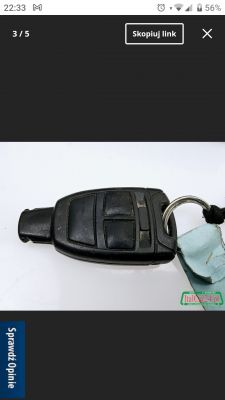 Czarny pilot samochodowy leżący na białym tle z brelokiem.