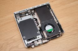 Otwarta obudowa mini komputera bez części górnej, ukazująca wnętrze z wentylatorem i komponentami elektronicznymi.