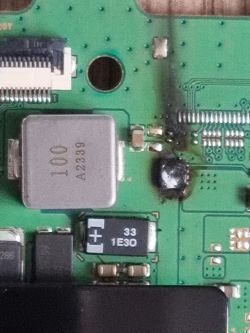 Zbliżenie płytki PCB z nadpalonym obszarem obok elementów SMD i cewki oznaczonej „100”