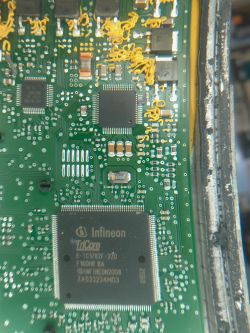 Zbliżenie na płytkę drukowaną sterownika skrzyni biegów z kilkoma układami scalonymi Infineon i brakiem rezonatora kwarcowego.