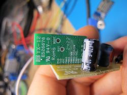 Close-up of an electronic circuit board with a green YX-12 module and a capacitor.