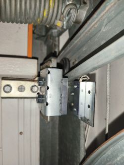 Zbliżenie na mocowanie kontaktronu Satel B-3 i magnesu na prowadnicy bramy segmentowej