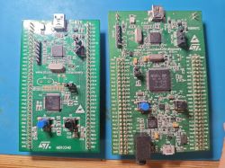 Two STM32 development boards with components and pin headers on a blue background.