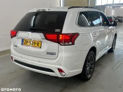 White Mitsubishi Outlander PHEV in a parking lot, rear view.