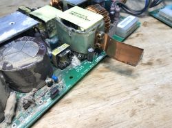 Fragment zasilacza impulsowego pochodzącego ze starego switcha, widoczne zakurzenie i ślady zanieczyszczeń na elementach elektronicznych.