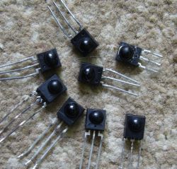 Several electronic receivers with three legs on a carpeted surface.