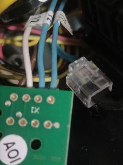 Zbliżenie na połączenia elektryczne, w tym przewody oznaczone numerami oraz zielona płytka z gniazdami.