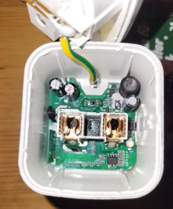 Interior of electrical device with PCB, capacitors, and metallic socket terminals