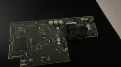 Green circuit board with various electronic components on a dark surface