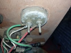 Węzeł kabli elektrycznych z trzema przewodami: zielonym, czerwonym i białym, podłączonymi do metalowego zacisku.