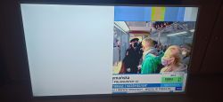 Obraz telewizora z problematycznym wyświetlaniem, częściowo biały ekran po lewej i fragment programu TV po prawej stronie.