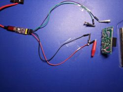 PCB connected with wires and alligator clips on a blue work mat