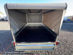 Inside a tarpaulin trailer with black floor and open rear on a gravel lot
