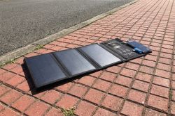 Foldable solar panel on a red brick sidewalk next to an asphalt road