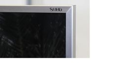 Zbliżenie na aluminiową ramkę telewizora z logo SUHD w prawym górnym rogu.