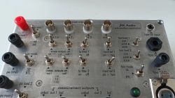 Panel przystawki pomiarowej wzmacniaczy audio z przełącznikami i złączami.