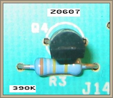 Widok zbliżeniowy na rezystor i element elektroniczny na płytce drukowanej.