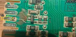 Zbliżenie płytki PCB ze śladami przypalenia i zaznaczonym uszkodzonym miejscem