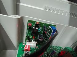 Zbliżenie na wnętrze obudowy z zieloną płytką PCB i podłączonymi przewodami