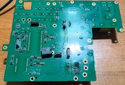 Zielona płytka PCB z kilkoma złączami i elementami elektronicznymi na drewnianym blacie