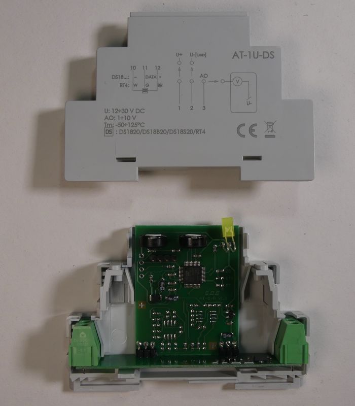 Moduł elektroniczny AT-1U-DS do montażu na szynie DIN, pokazany w otwartej obudowie z widoczną płytką PCB.