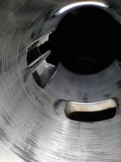 Wnętrze cylindra silnika dwusuwowego z widocznymi rysami i kanałami