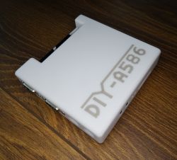 White DIY-A586 case with visible ports, placed on a wooden surface.