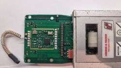 Płytka drukowana z elektroniką i przewodem spiralnym, połączona z metalowym modułem oznaczonym Lindner &amp; Fischer.