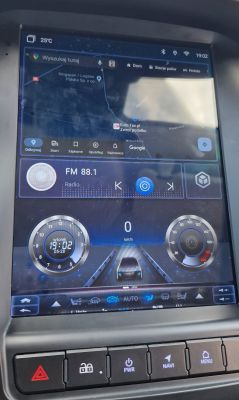 Wyświetlacz radia z systemem Android w samochodzie, pokazujący mapę i odtwarzacz muzyki.