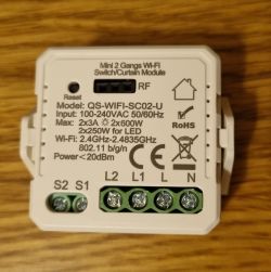 Mini Wi-Fi Switch Module QS-WIFI-SC02-U Mini Wi-Fi switch module QS-WIFI-SC02-U on a wooden surface.