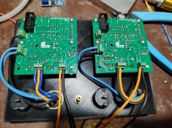 Dwa moduły PCB przymocowane do czarnej podstawy z przewodami i złączami