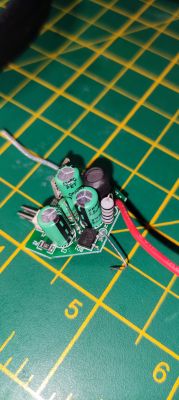 Image of a PCB with several green capacitors and wires on a work mat background.