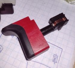 Zbliżenie na część przełącznika wkrętarki na tle papieru milimetrowego.