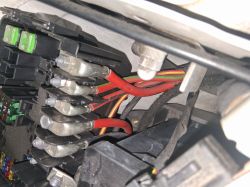 Close-up of a fuse box with visible colorful wires and metal clamps.