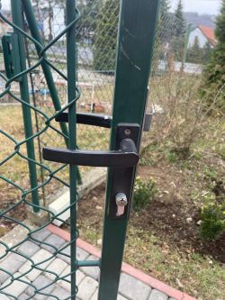 Metalowa furtka z zamontowaną klamką i zamkiem.