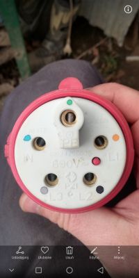 Gniazdo elektryczne z oznaczeniami na płycie z porcelany i czerwonym przyciskiem.