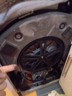 Wnętrze pralki z widocznym zabrudzeniem wokół koła pasowego i silnika