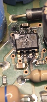Zbliżenie płytki PCB z nadpalonym układem scalonym SOIC-8 i śladami spalenizny