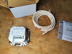 WT200-16A-W-wifi thermostat base with terminals, coiled wired sensor, and manual on a wooden table