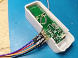 Close-up of a circuit board with attached wires inside a white case.