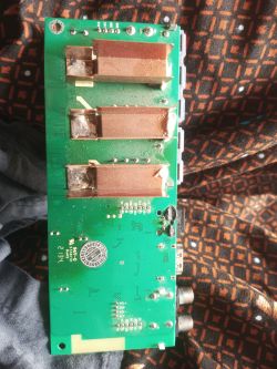 Green circuit board with three large coils and visible burn marks near one component.