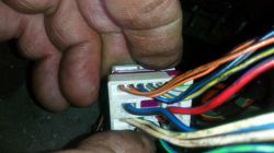 Ręce trzymające złącze elektryczne z różnokolorowymi kablami.