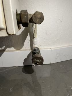 Close-up of a radiator valve, showing its dirty surface.